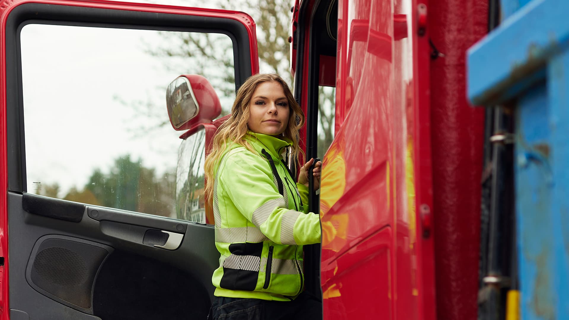 Kvinna med varselkläder som står bredvid en lastbil