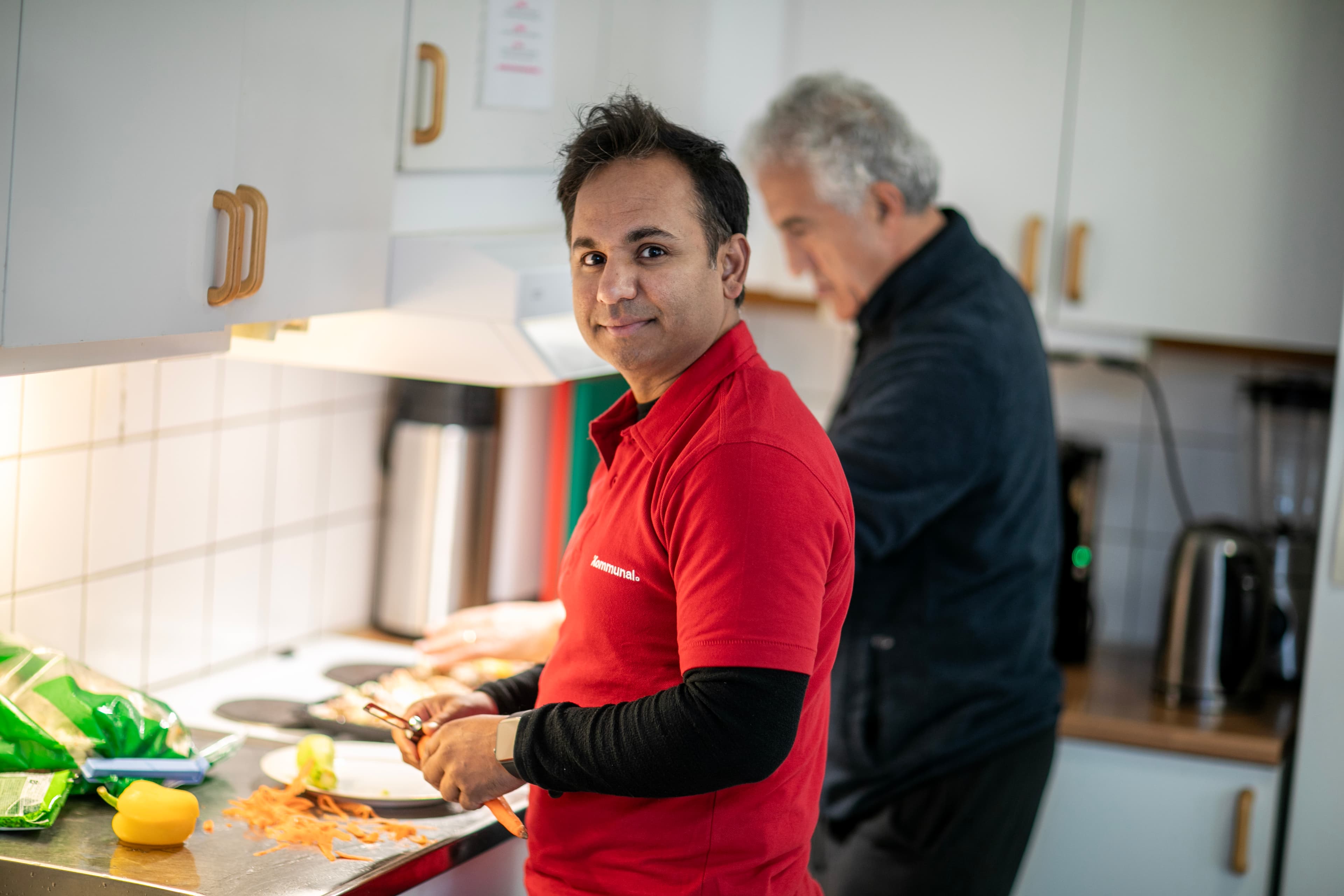 Man i Kommunal tröja står tillsammans med en annan man och lagar mat
