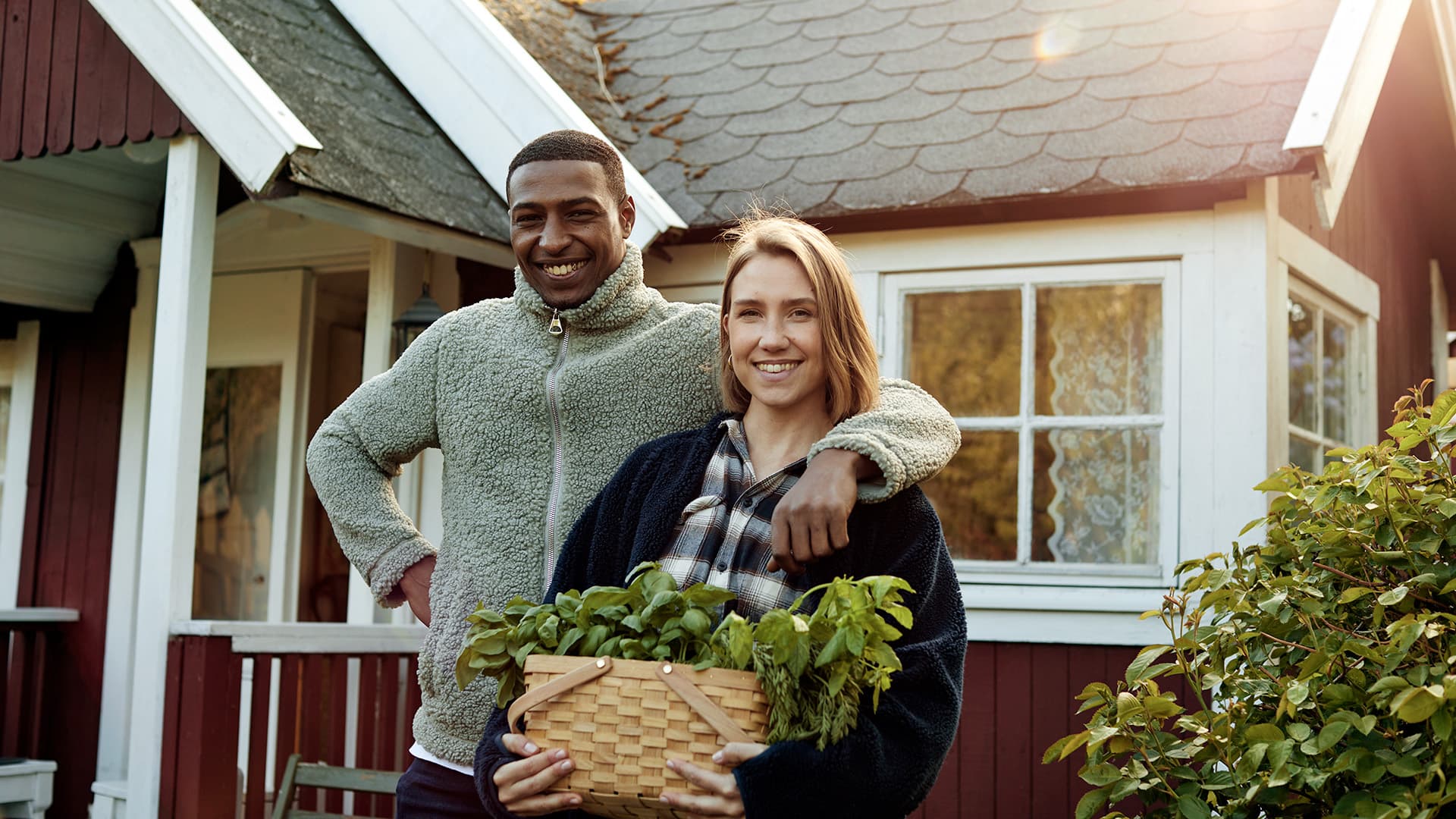 Kvinna och man som står framför en röd stuga.