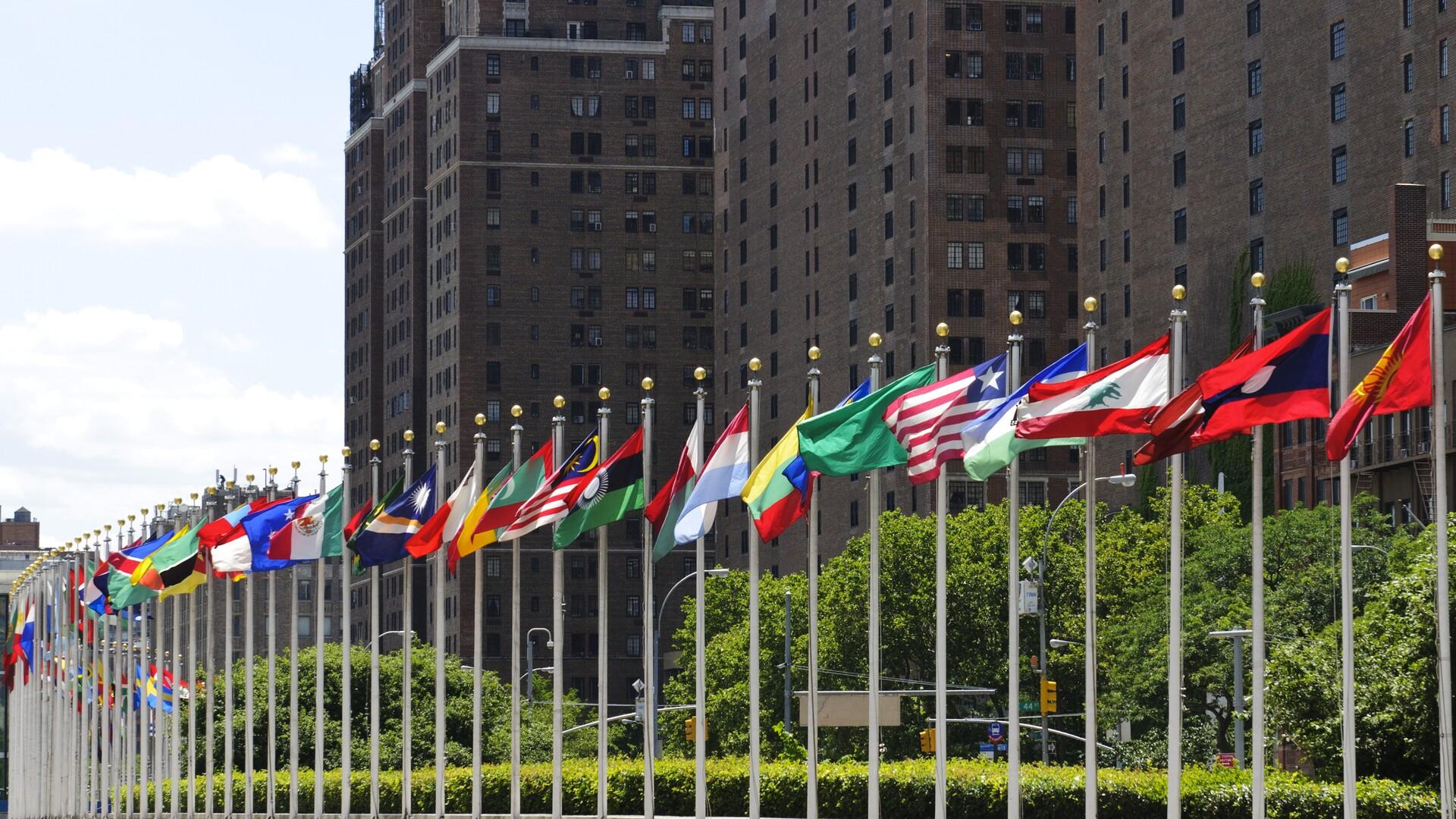 Flaggor från olika länder utanför stor byggnad.
