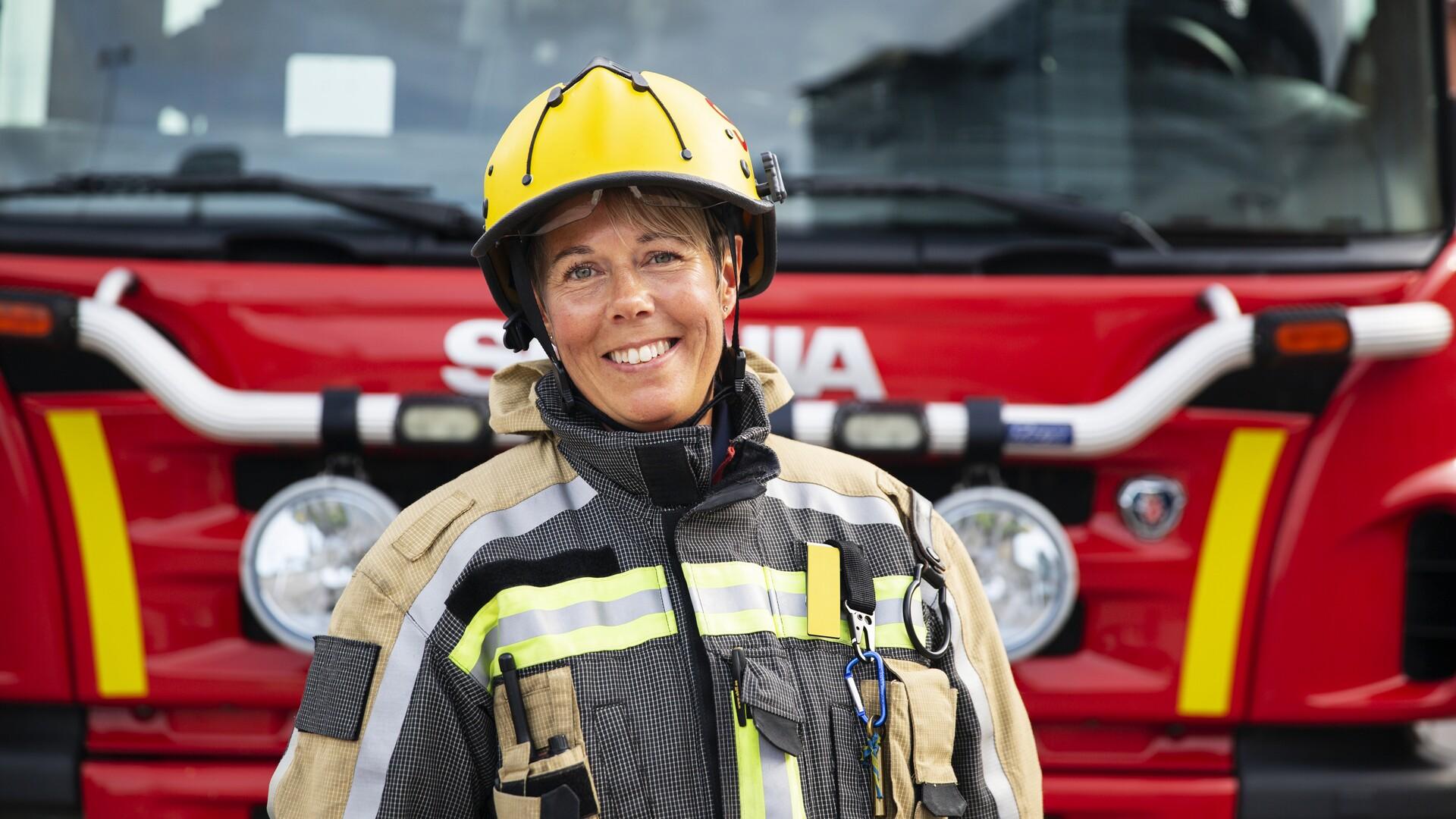 Kvinnlig brandman framför brandbil.