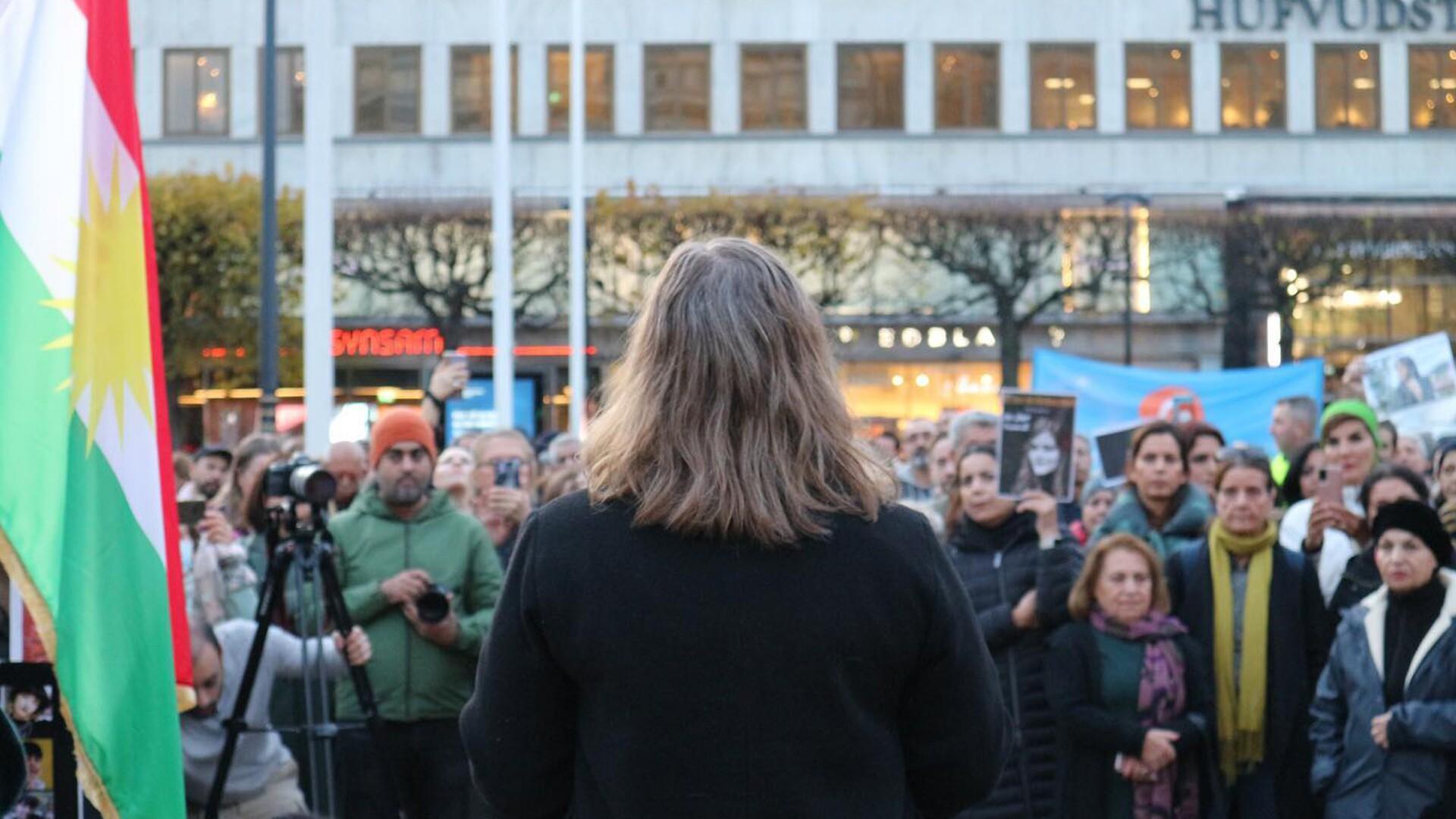 Malin Ragnegårds på en scen inför deltagare på demonstration.