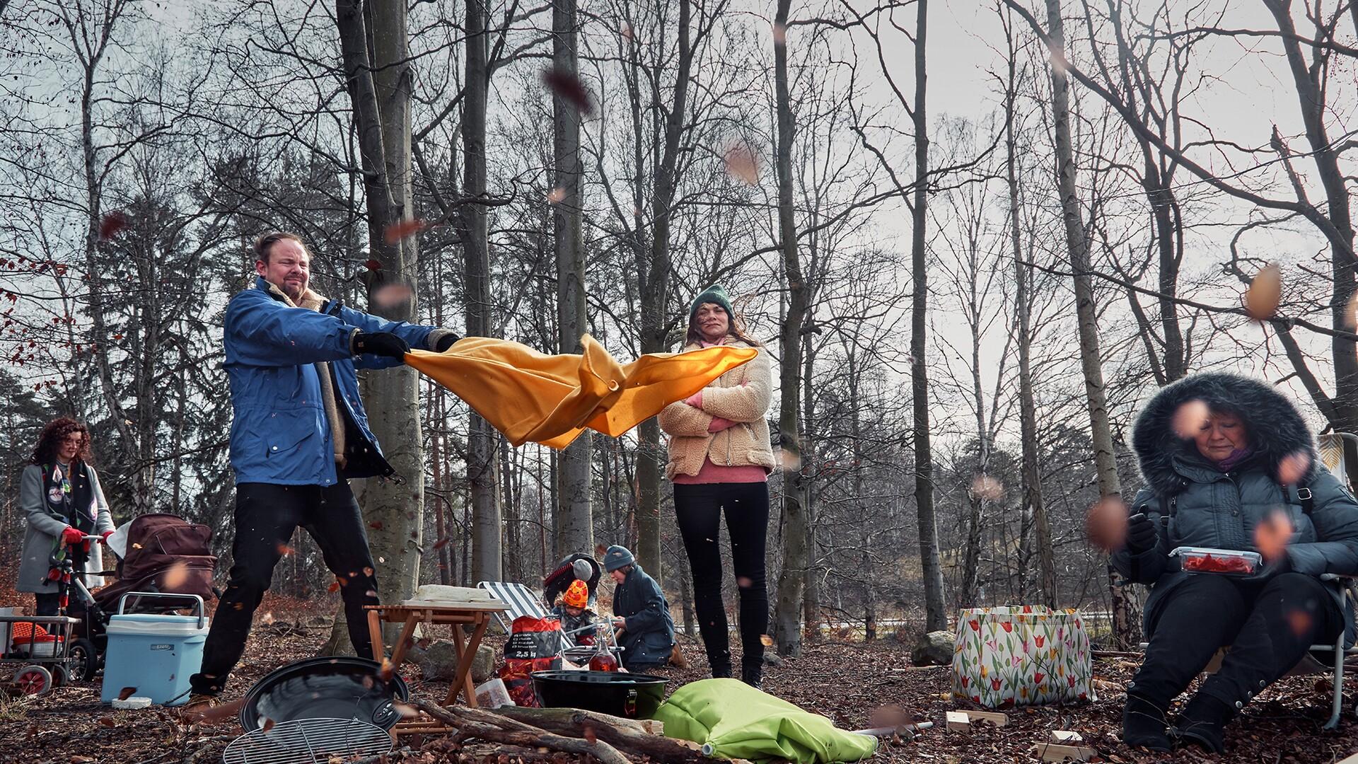 Man och kvinna försöker slå upp ett tält i skogen. 
