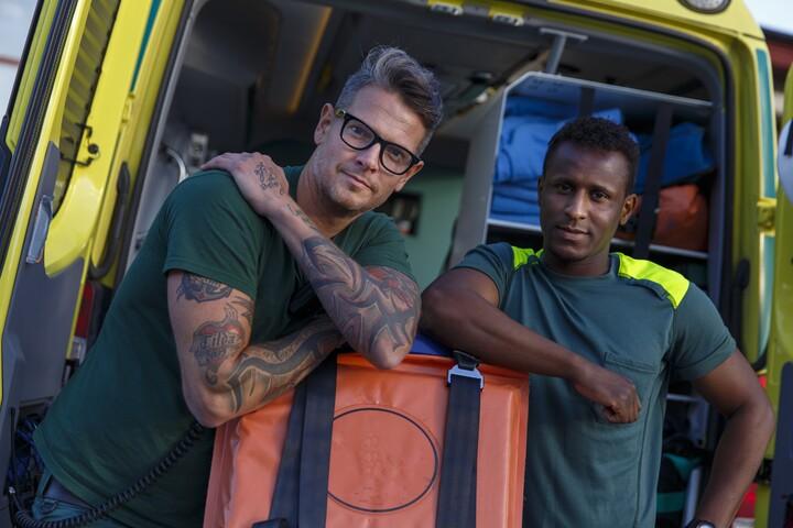 Bild på två manliga ambulansförare på baksidan av en ambulans.