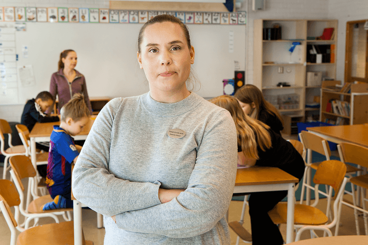 Kvinna med korslagda armar i skolmiljö