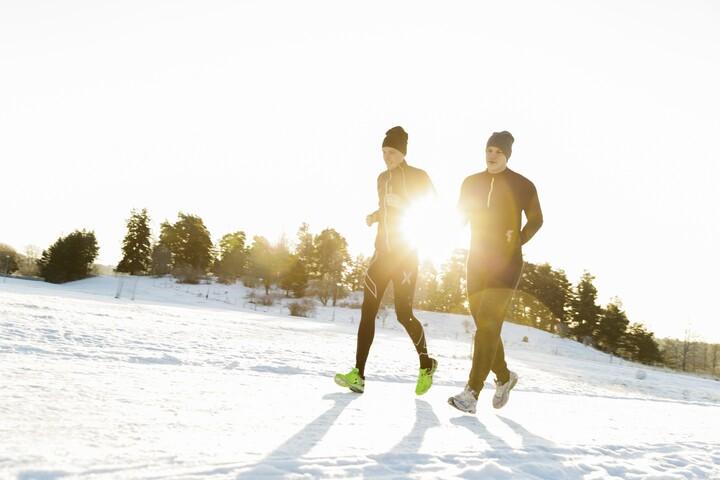 Man och kvinna löper i vinterlandskap.