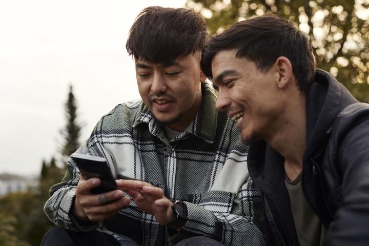 Två killar tittar på en mobiltelefon.
