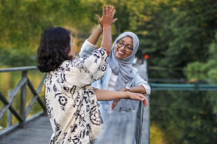 Två kvinnor gör high five på en bro.