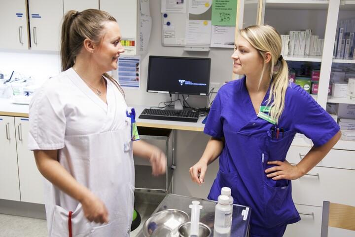 Två kvinnor tittar på varandra i vårdmiljö.