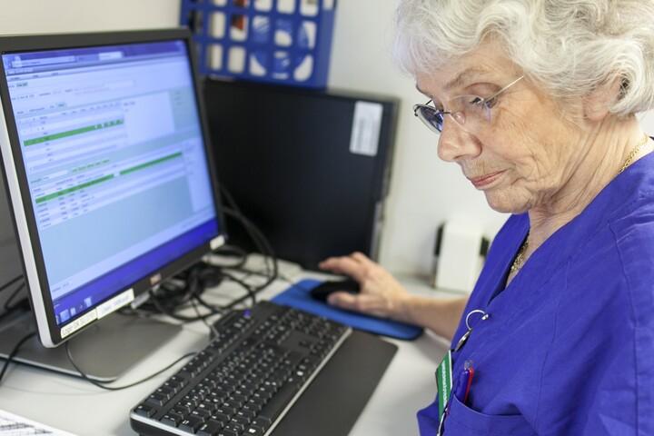 Undersköterska vid en dator.