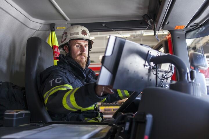 Brandman pekar på datorskärm i förarhytten i brandbil.