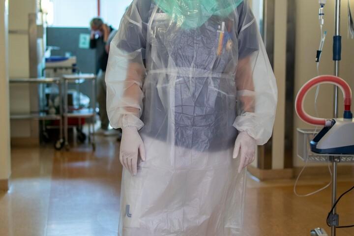 Kvinna i skyddsutrustning i sjukhuskorridor. 