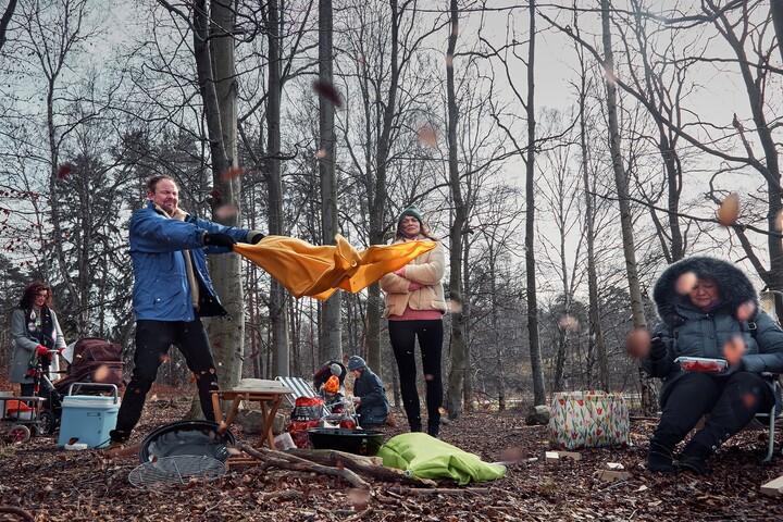 Man och kvinna försöker slå upp ett tält i skogen. 